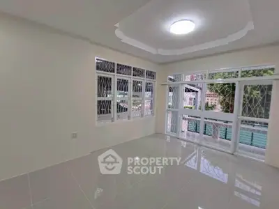 Spacious living room with large windows and glossy tile flooring