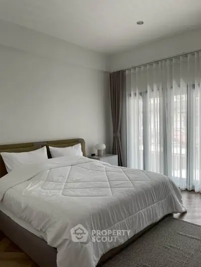 Spacious bedroom with elegant decor and large windows for natural light