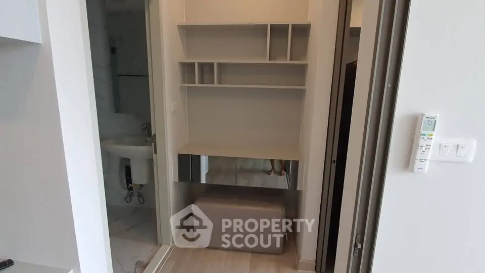 Modern apartment interior with compact bathroom and stylish shelving unit.