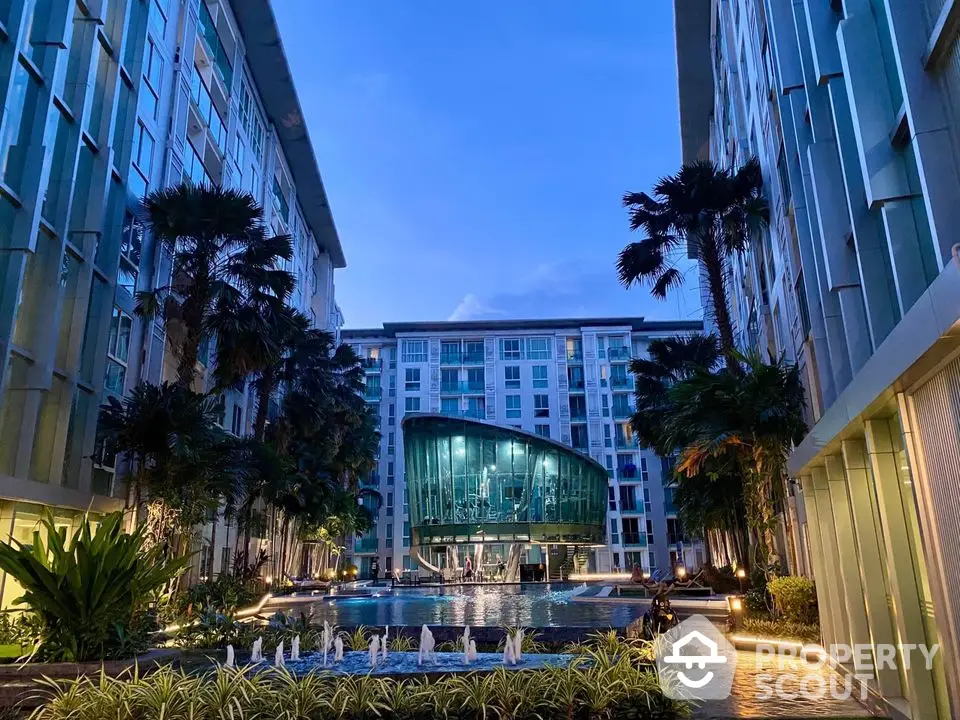 Luxurious modern apartment complex with stunning pool and lush landscaping at dusk.