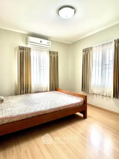 Bright and airy bedroom with wooden flooring and large windows in a modern apartment.