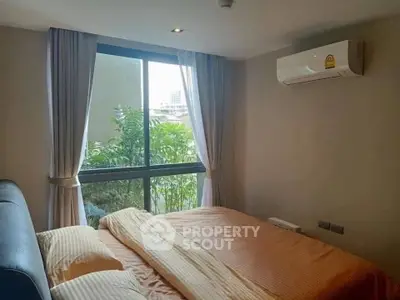 Cozy bedroom with large window and air conditioning in modern apartment