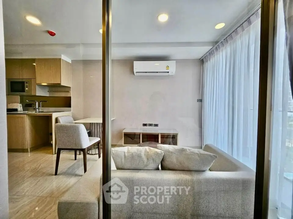 Modern living room with open kitchen and large windows in a stylish apartment.