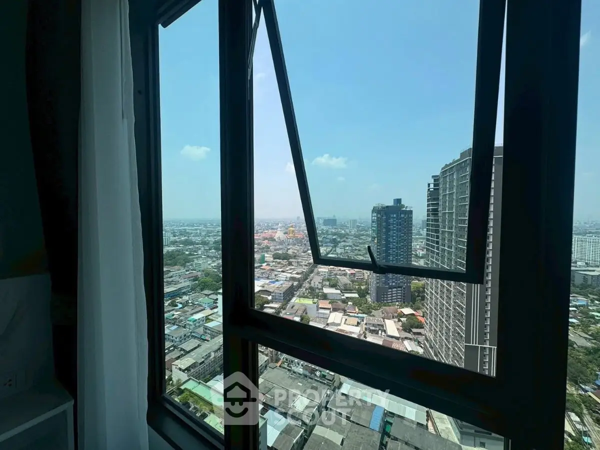 Stunning cityscape view from high-rise apartment window, showcasing urban skyline and clear blue sky.