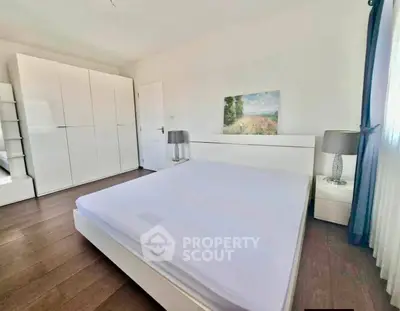 Spacious bedroom with modern white furniture and natural light