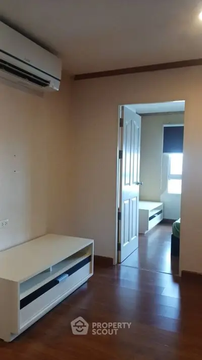 Modern apartment interior with wooden flooring and air conditioning, featuring a cozy bedroom view.