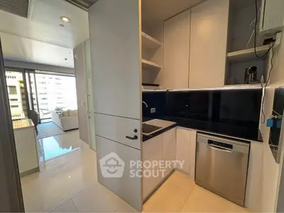 Modern kitchen with sleek design and adjacent bright living room in urban apartment.