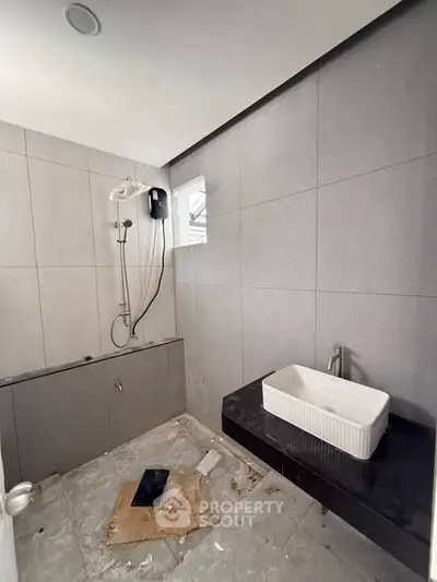 Modern bathroom with sleek gray tiles and contemporary fixtures, featuring a stylish sink and shower area.