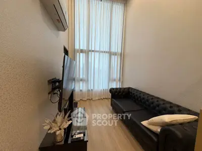 Modern living room with high ceilings, leather sofa, and wall-mounted TV in a cozy apartment.
