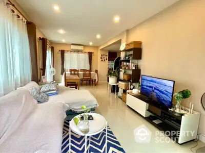 Spacious living room with modern decor and natural light, featuring a cozy seating area and entertainment setup.