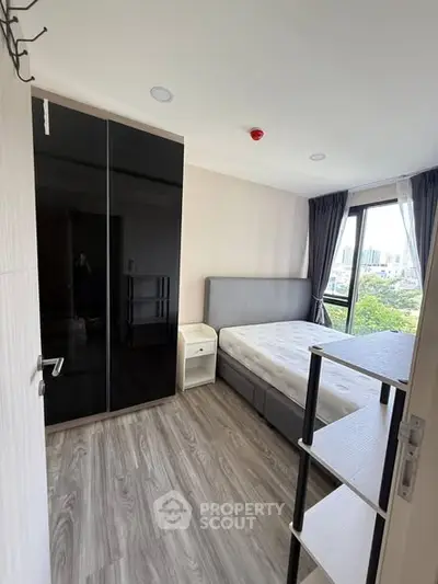 Modern bedroom with city view, featuring sleek black wardrobe and cozy bed.