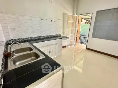 Spacious kitchen with modern sink and open layout leading to balcony