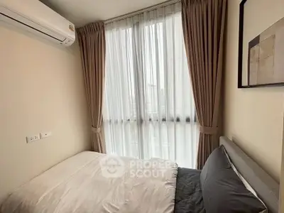 Cozy bedroom with large window and modern air conditioning unit, perfect for natural light lovers.