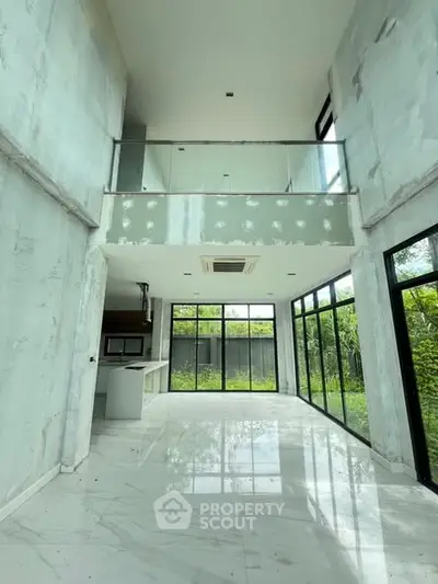 Spacious modern living room with high ceilings and large windows overlooking garden