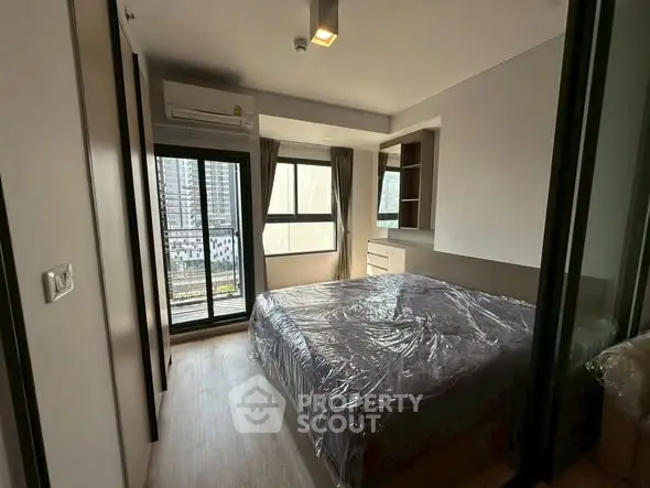 Modern bedroom with large windows and balcony access in urban apartment