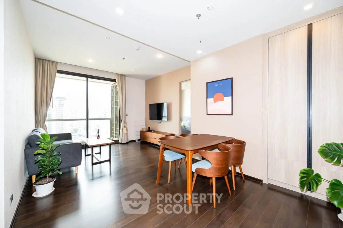 Spacious modern living room with large window and stylish furniture in a high-rise apartment.