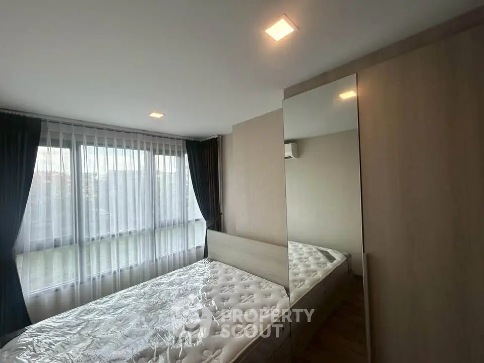 Spacious bedroom with large windows and modern furnishings in a stylish apartment.