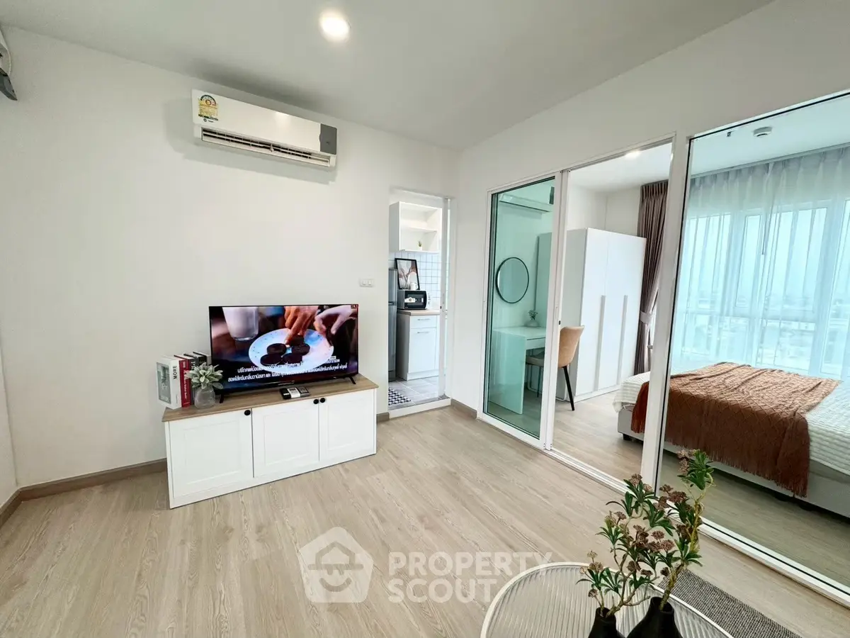 Modern living room with TV, air conditioning, and view into bedroom with natural light.
