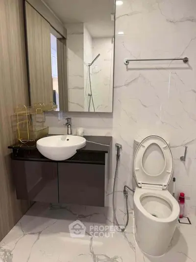 Modern bathroom with sleek fixtures and marble tiles, featuring a stylish vanity and toilet.