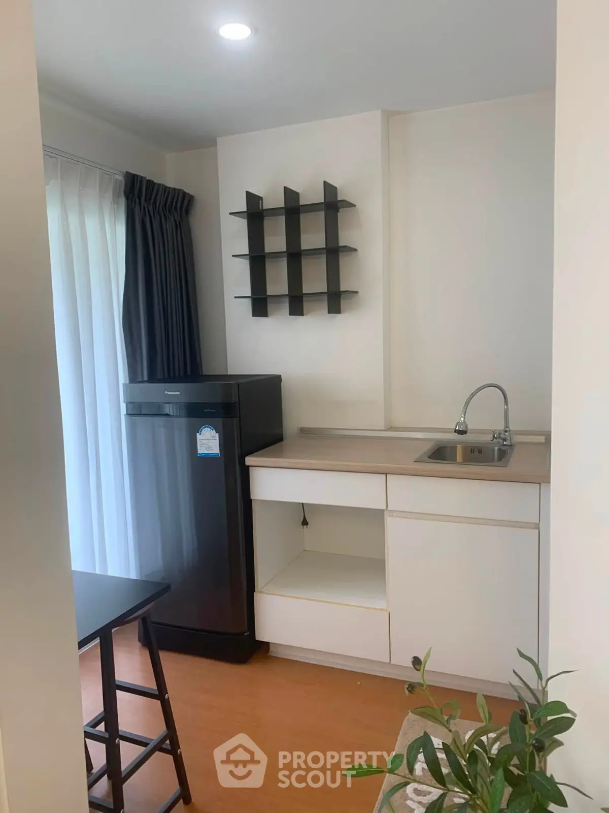 Modern kitchen with sleek cabinetry and compact design, featuring a black refrigerator and stylish shelving.