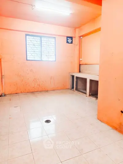 Spacious kitchen area with tiled flooring and ample natural light, ideal for customization.
