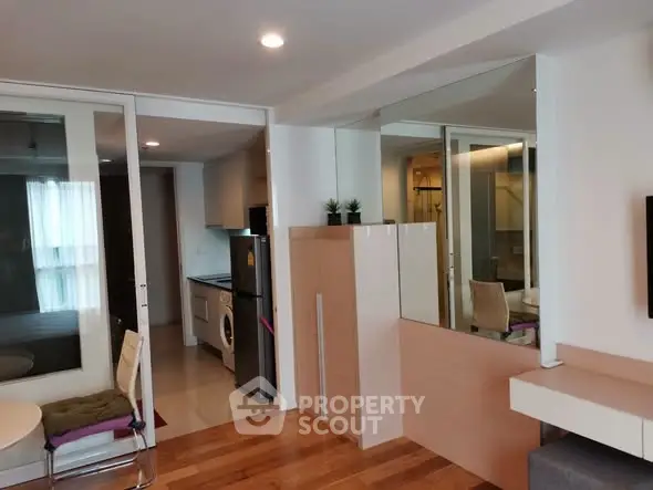 Modern apartment interior with open layout featuring kitchen and living area, wooden flooring, and stylish decor.