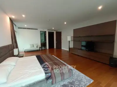 Spacious modern bedroom with wooden flooring and stylish furniture