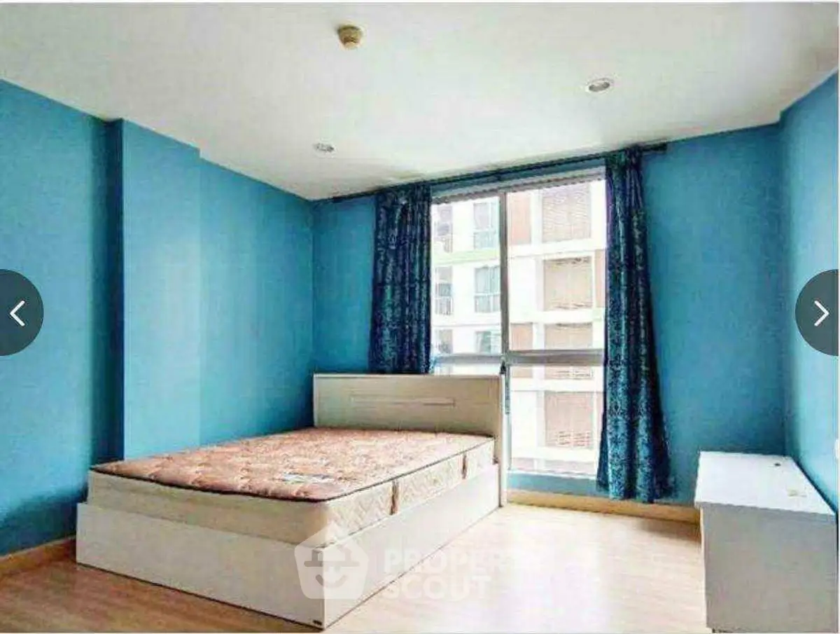 Spacious bedroom with blue walls and large window in modern apartment