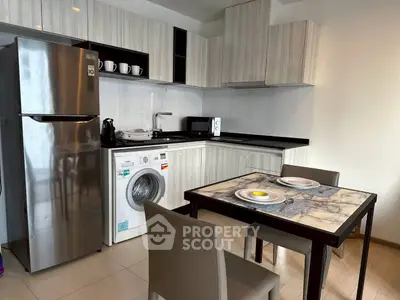 Modern kitchen with stainless steel fridge, washing machine, and dining area