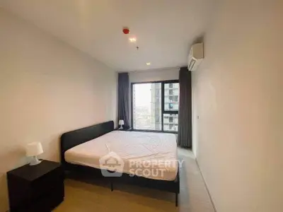 Spacious bedroom with large window offering city views, modern furnishings, and ample natural light.