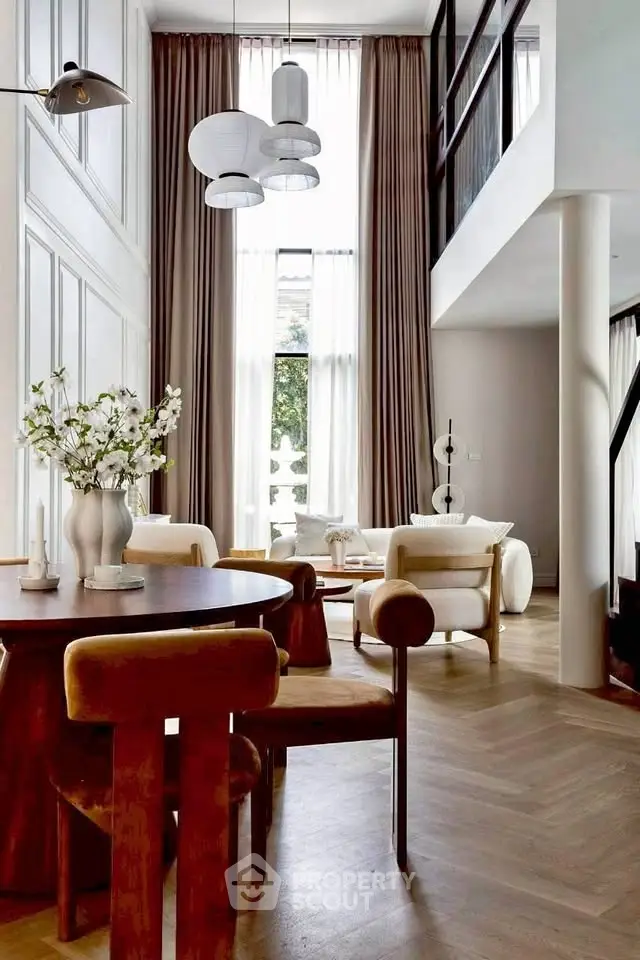 Luxurious living room with high ceilings and elegant decor, featuring modern furniture and large windows.