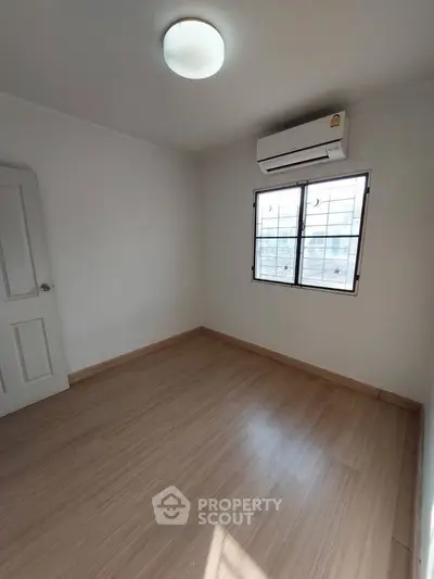 Spacious empty room with wooden flooring and air conditioning, perfect for customization.