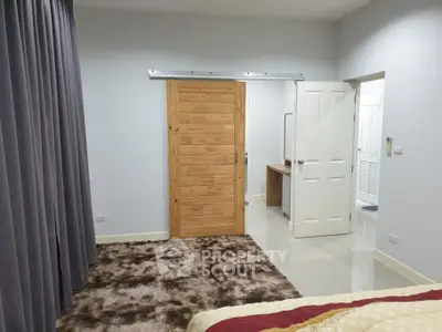 Modern bedroom with sliding wooden door and plush carpet