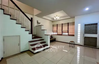 Spacious living room with elegant staircase and modern lighting, perfect for family gatherings.