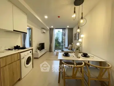 Modern open-plan living room with kitchen and dining area, featuring stylish lighting and a washing machine.