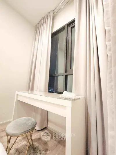 Elegant study nook with modern desk and plush stool by a large window, perfect for productivity.