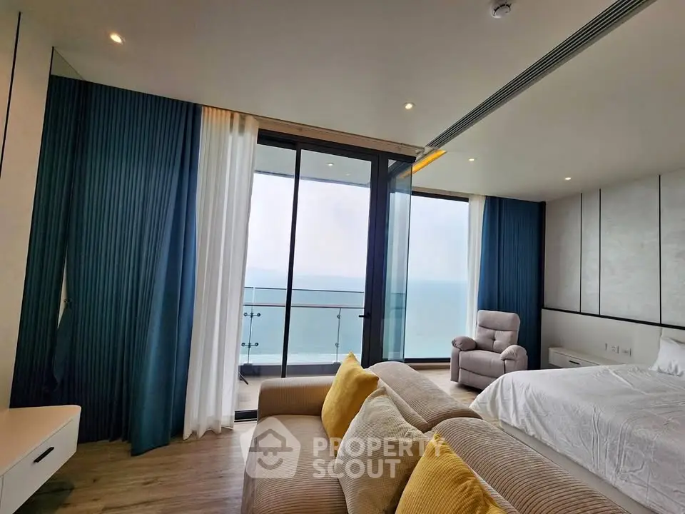 Luxurious bedroom with ocean view and modern decor, featuring floor-to-ceiling windows and elegant furnishings.