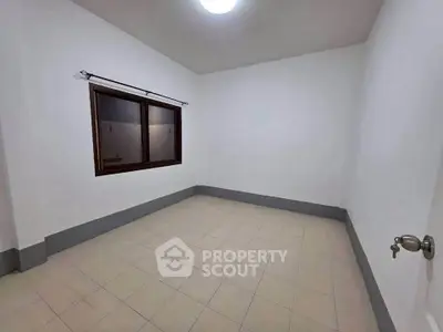 Spacious empty room with tiled floor and large window, perfect for customization.