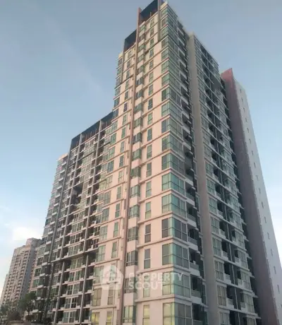 Modern high-rise residential building with sleek glass facade and multiple balconies.