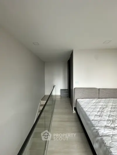 Modern minimalist bedroom with sleek glass railing and neutral tones