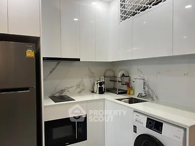 Modern kitchen with sleek white cabinets, marble backsplash, and built-in appliances.