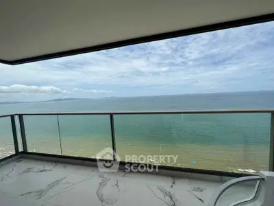 Stunning oceanfront balcony with panoramic sea views and modern glass railing.