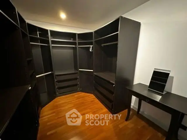 Spacious walk-in closet with sleek dark shelving and wooden floor
