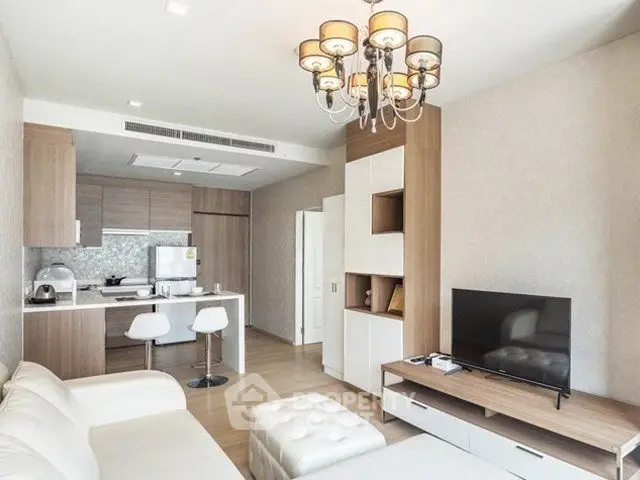 Modern living room with open kitchen, stylish chandelier, and cozy seating area.