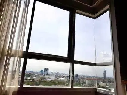 Stunning corner unit with panoramic city view through large windows.