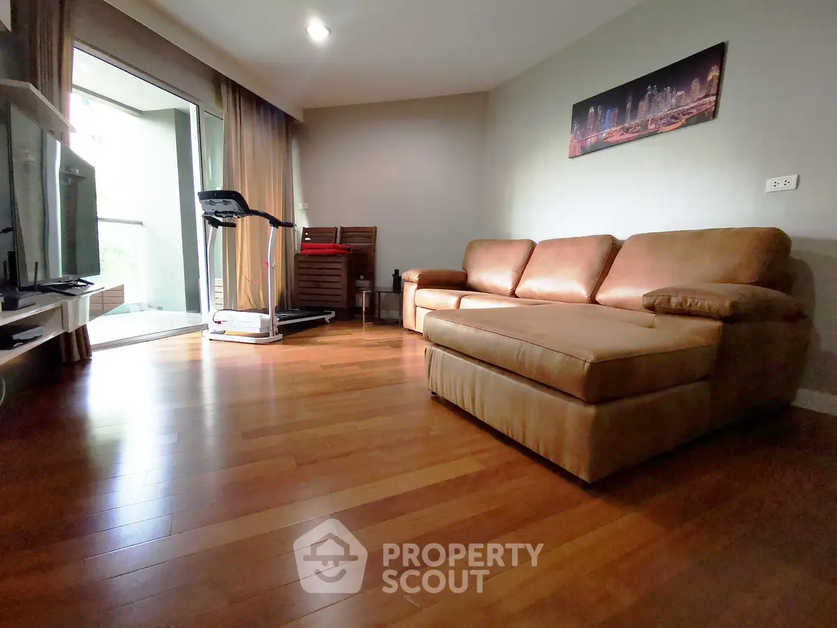 Spacious living room with hardwood floors and cozy sofa in modern apartment