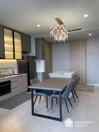 Elegant modern kitchen with integrated appliances, sleek cabinetry, and a stylish dining area complemented by a chic chandelier.