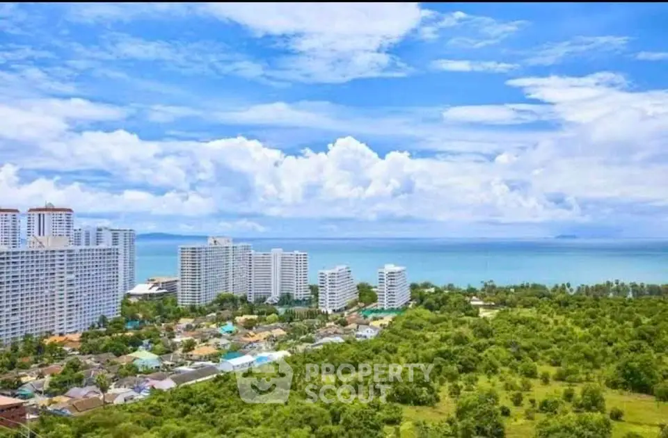 Stunning ocean view from high-rise building overlooking lush greenery and coastline.