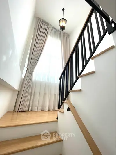 Elegant staircase with wooden steps and modern railing in bright, airy home interior.