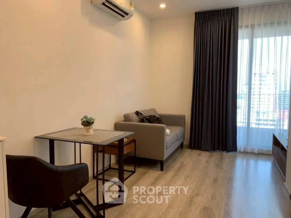 Modern living room with cozy seating and natural light from large window.